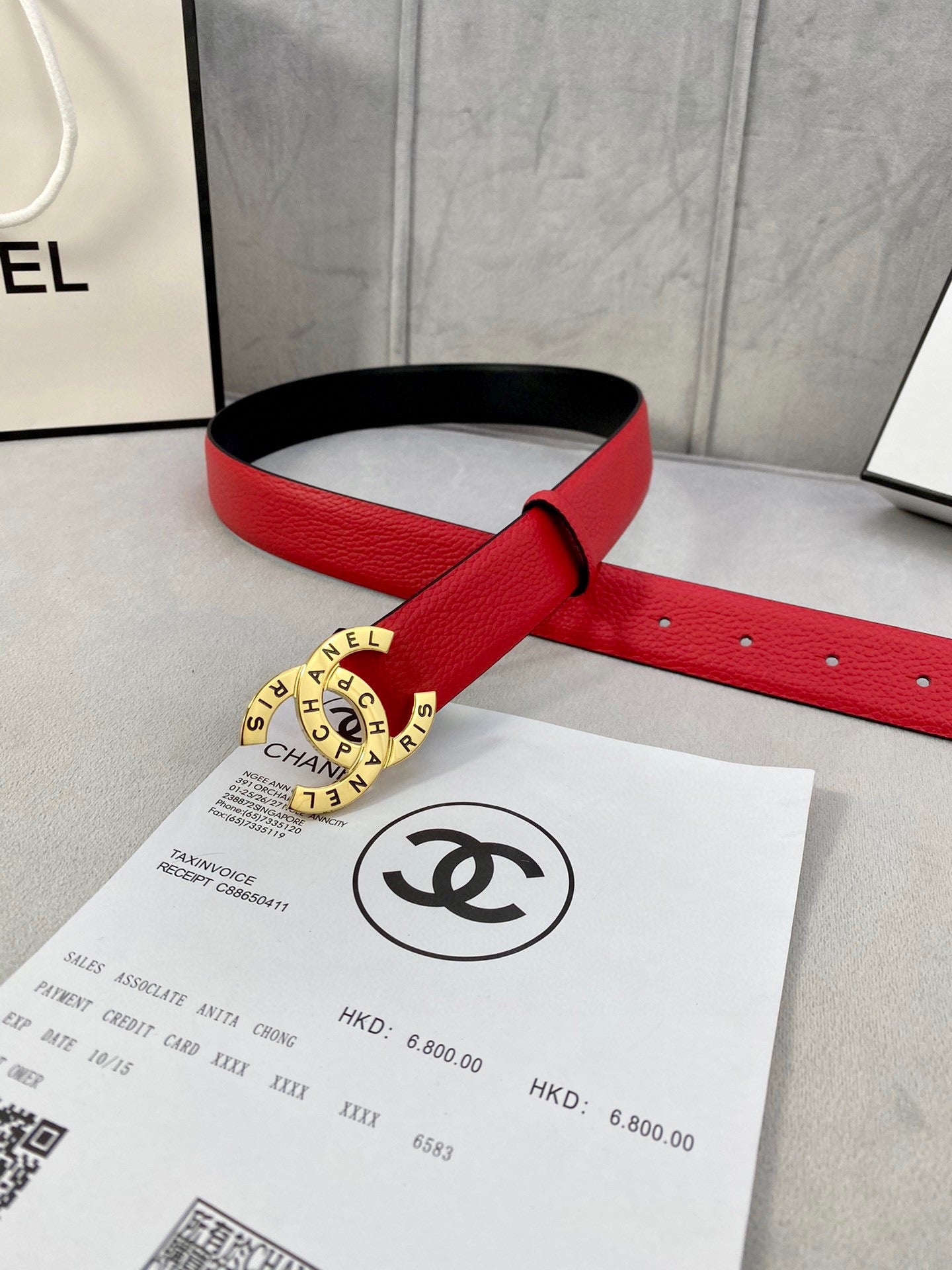 Chanel belt on red leather strap with gold circular CHANEL buckle and perforated holes.