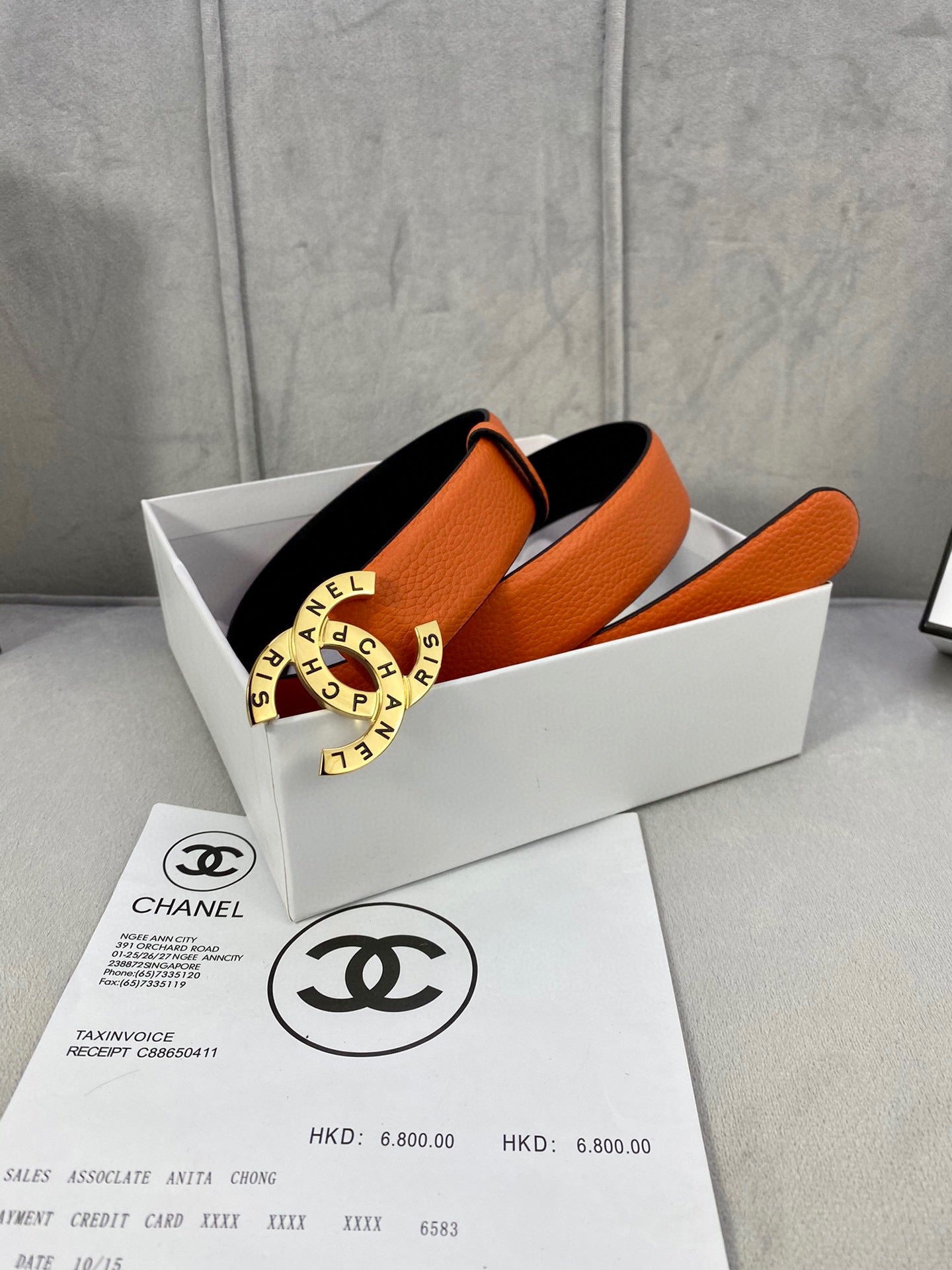 Orange leather Chanel belt with black underside and round logo buckle