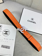 Orange Chanel belt laid across box, black lining and round logo buckle visible