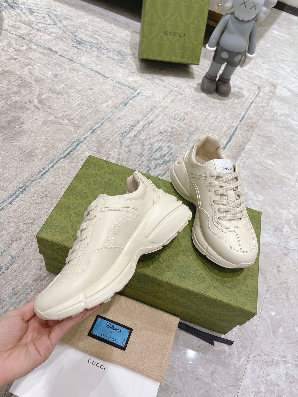 Two white Gucci unisex lace-up sneakers with side graphic and chunky sole
