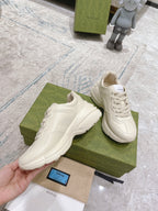 Two white Gucci unisex lace-up sneakers with side graphic and chunky sole