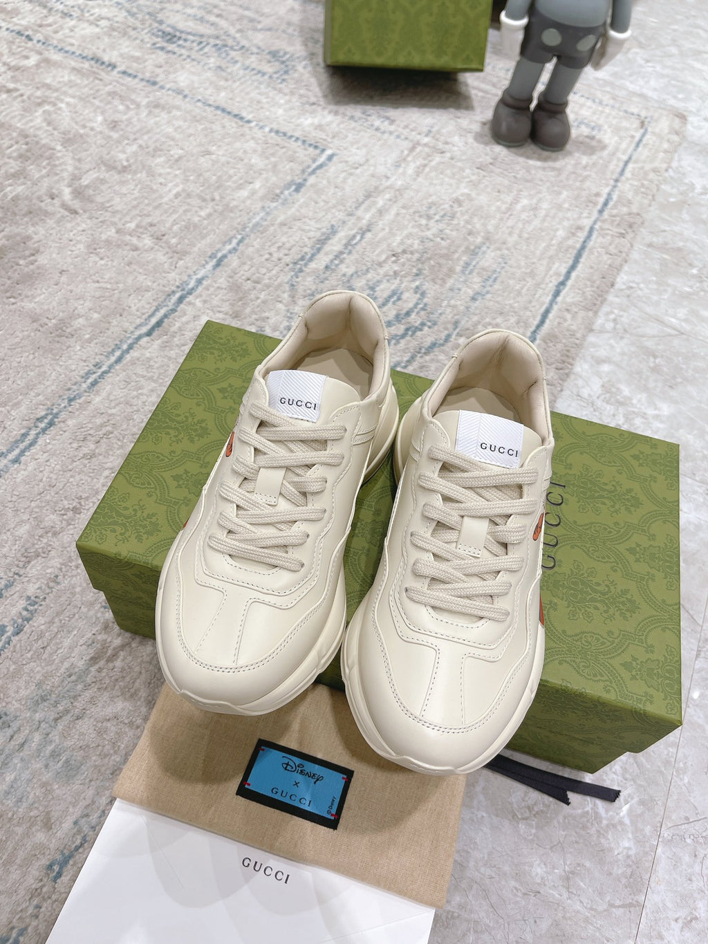 Pair of white Gucci unisex lace-up sneakers with colorful logo graphic on box