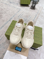 Pair of white Gucci unisex lace-up sneakers with colorful logo graphic on box