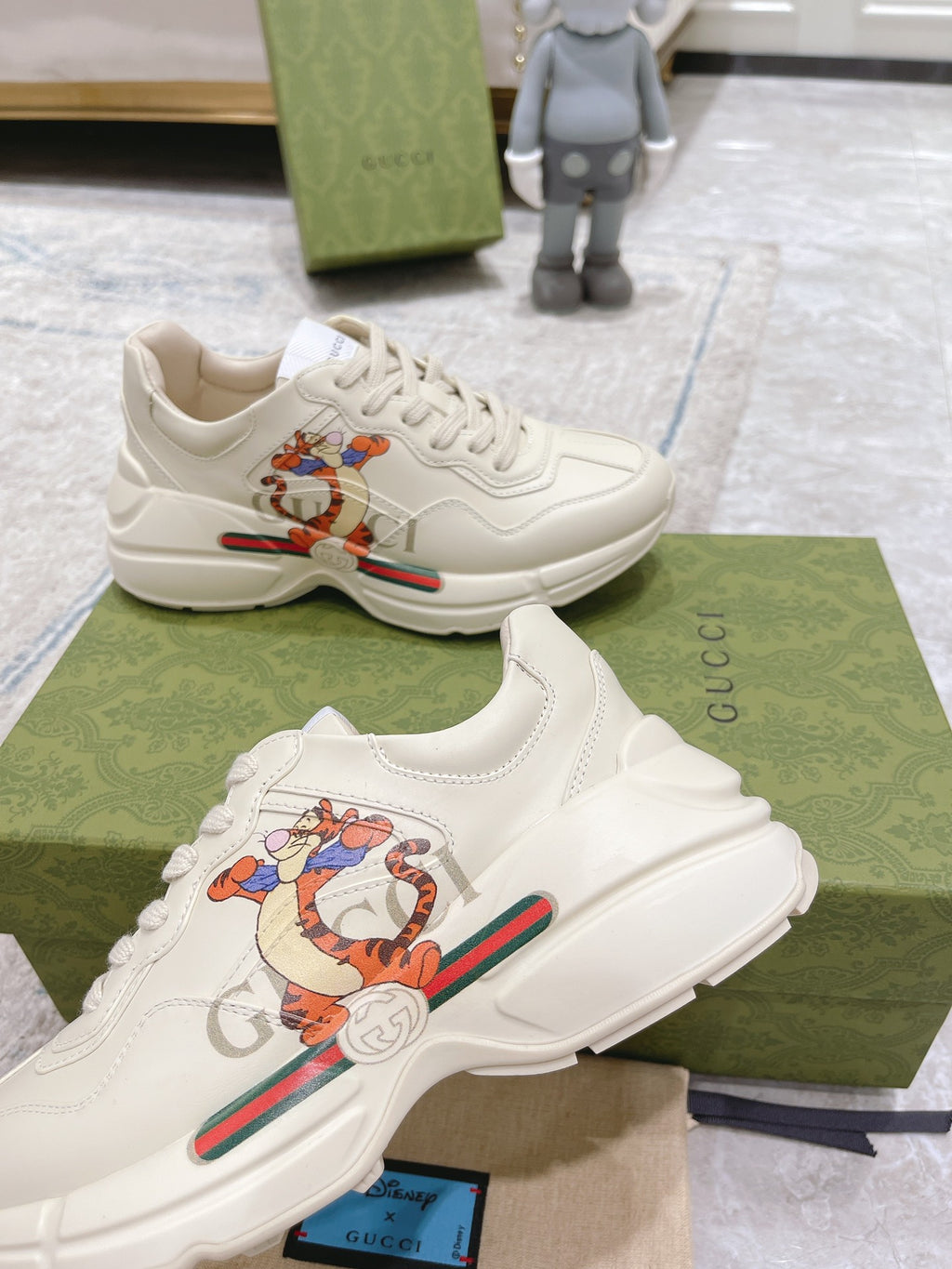 Close pair of white Gucci unisex sneakers with colorful cartoon patch, lace-up