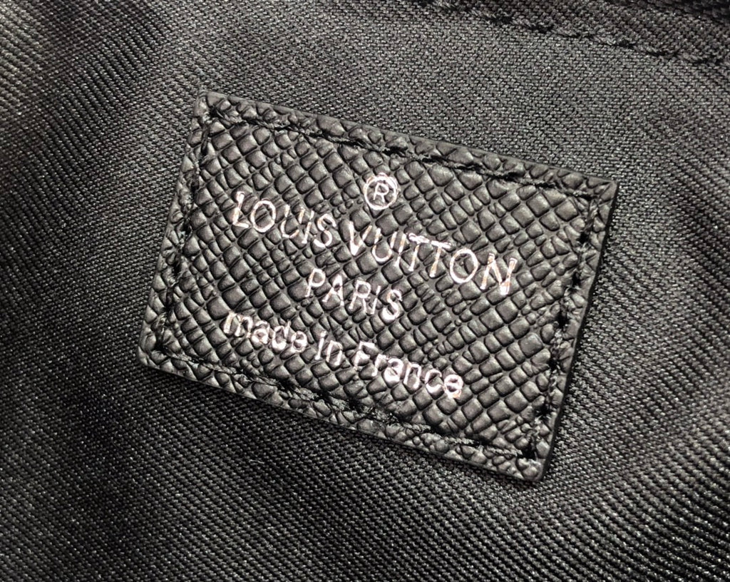 Men's Louis Vuitton tote bag close-up of logo fabric label with “Louis Vuitton Paris”