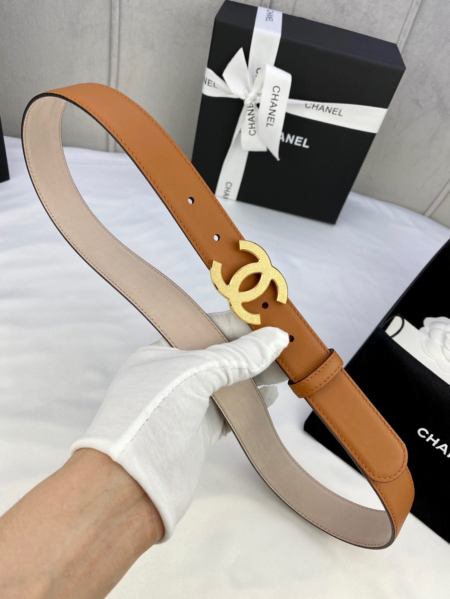 Tan leather belt with gold-tone CC buckle and punched holes