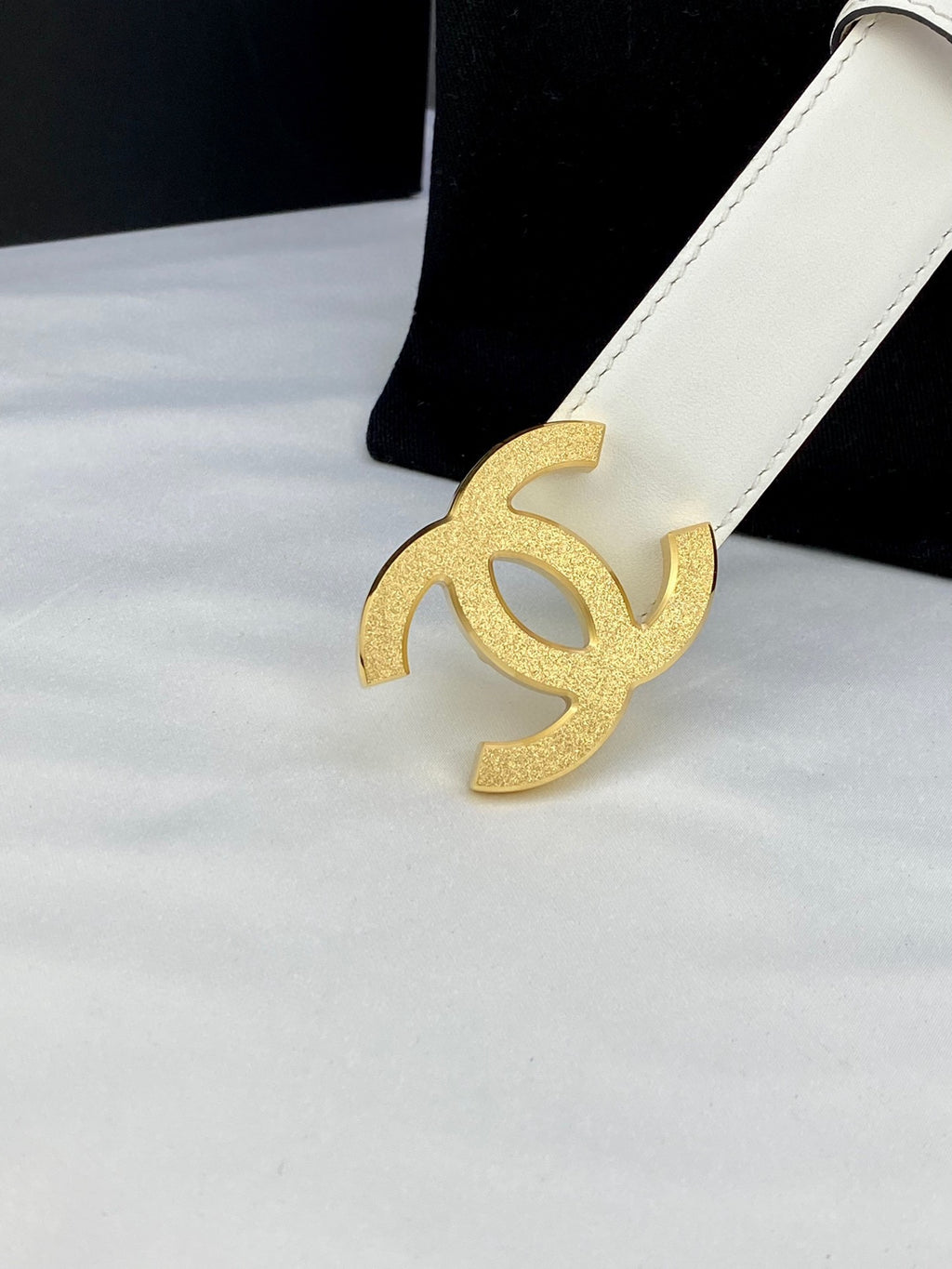 Chanel belt buckle in gold tone with CC logo on white leather strap and holes