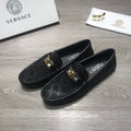 Black Versace loafers with gold buckle detail and textured logo upper.