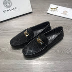Black Versace loafers with gold buckle detail and textured logo upper.