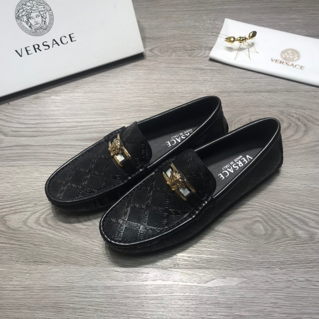 Black Versace loafers with gold buckle detail and textured logo upper.