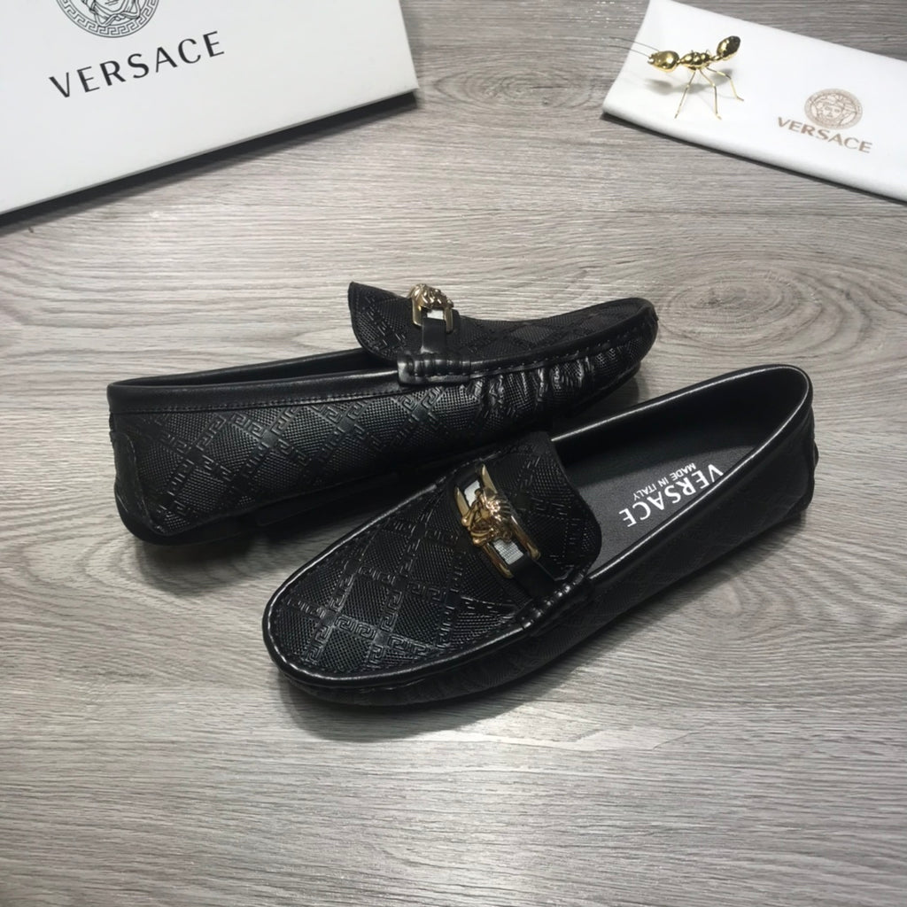 Black Versace loafers, side view, with gold buckle ornament on textured upper.