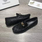 Black Versace loafers, side view, with gold buckle ornament on textured upper.