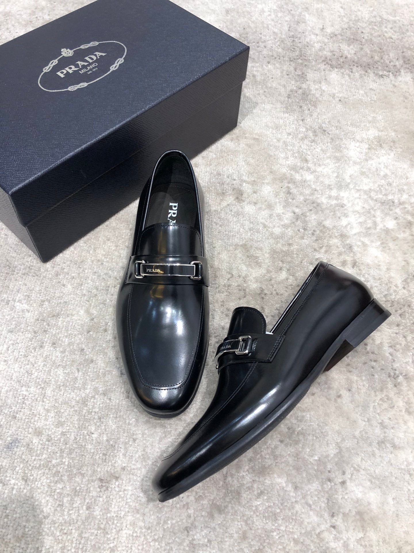 Prada unisex black leather loafers with metal buckle strap, front view