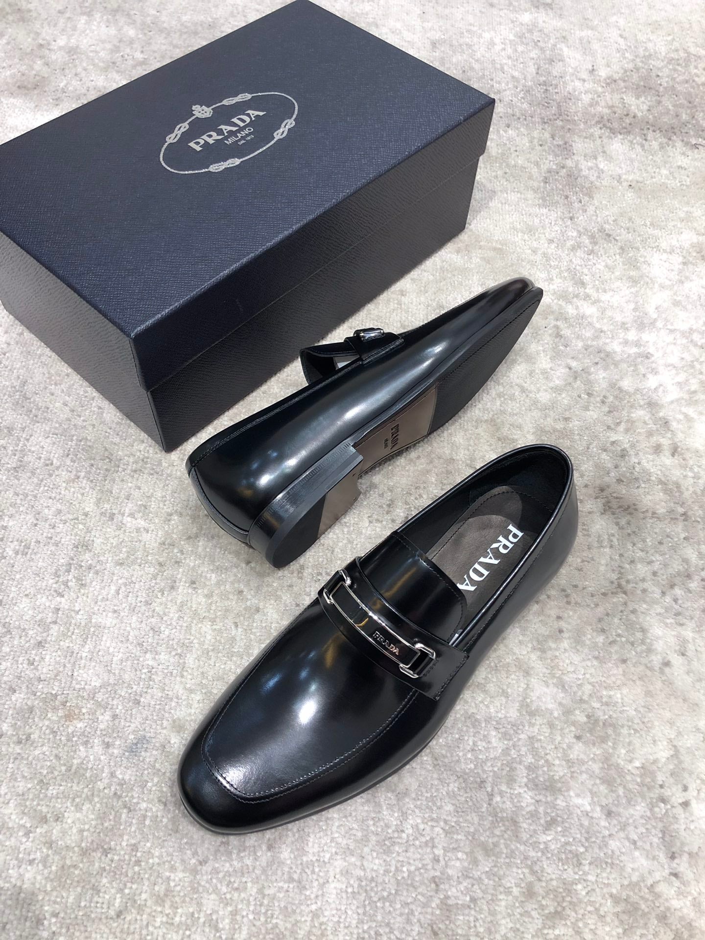 Prada unisex black leather loafers with buckle strap, heel side profile