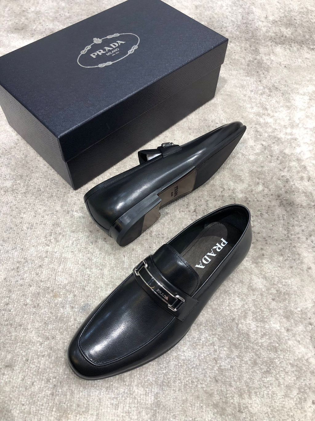 Prada unisex loafers, black leather slip-on with buckle strap, heel visible