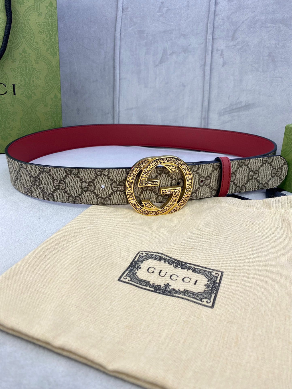 Gucci belt with beige GG canvas, red leather edge, round gold-tone G buckle.