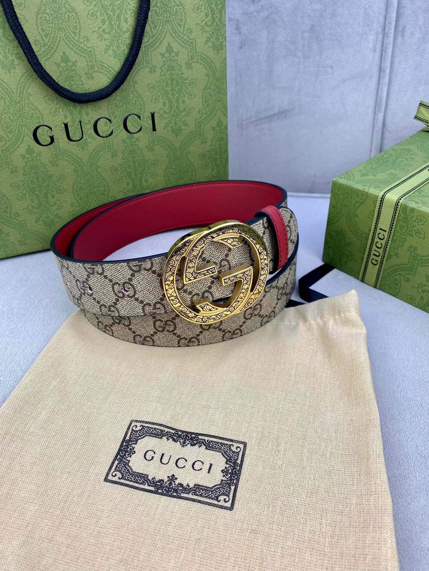 Gucci belt coiled: beige GG canvas with red leather and gold-tone G buckle.