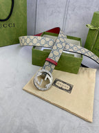 Gucci GG canvas belt with red leather strap and silver-tone G buckle, laid on pouch