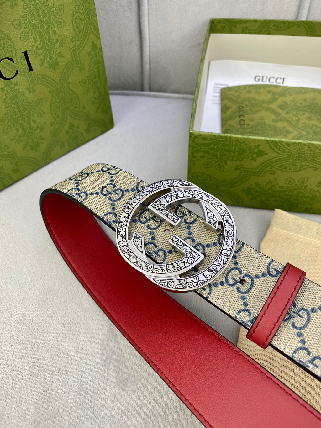 Gucci GG canvas belt with red leather strap and large silver buckle, angled view