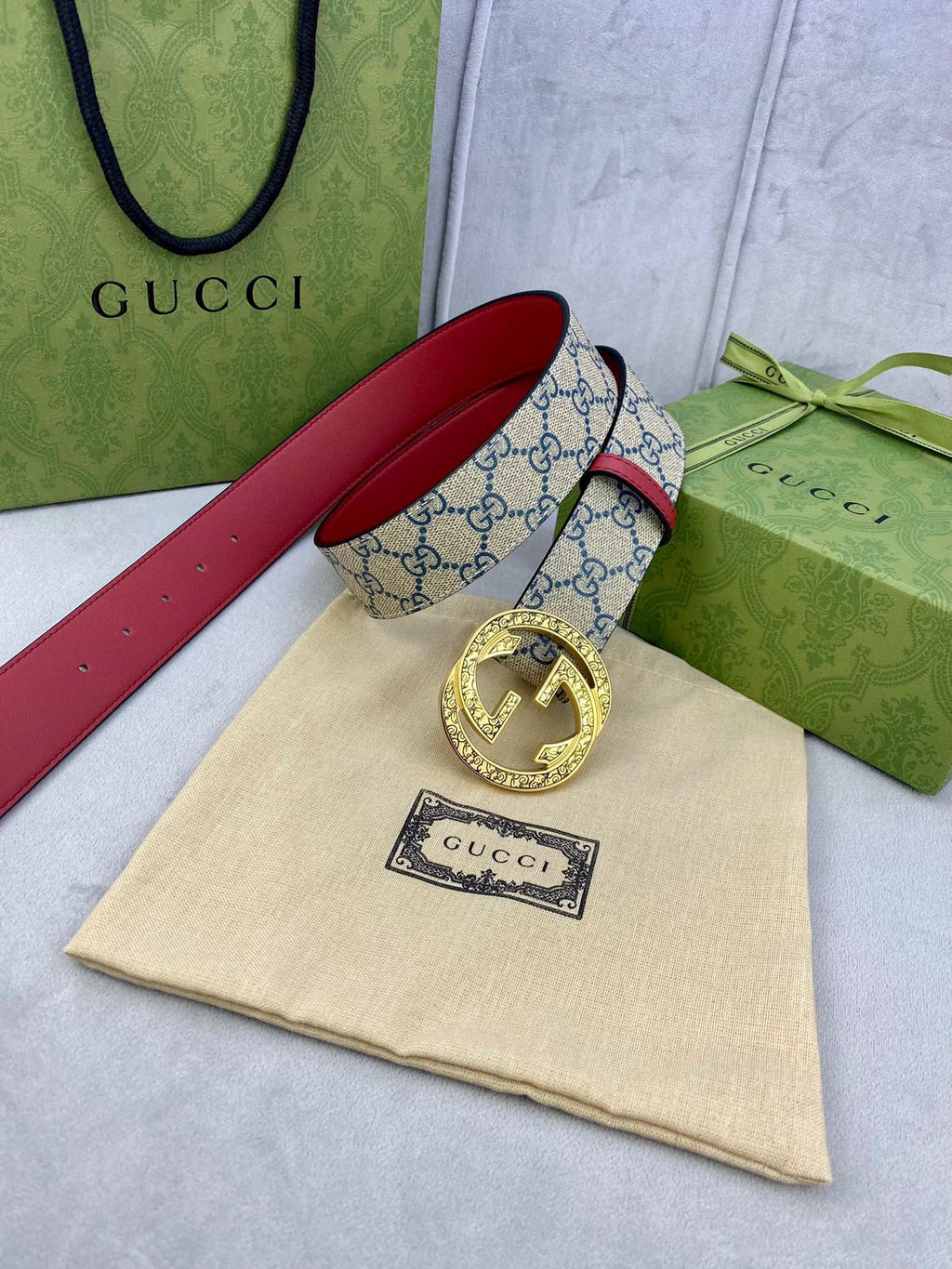 Gucci GG canvas belt with red leather strap and gold-tone buckle, laid flat