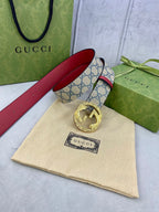 Gucci GG canvas belt with red leather strap and gold-tone buckle, laid flat