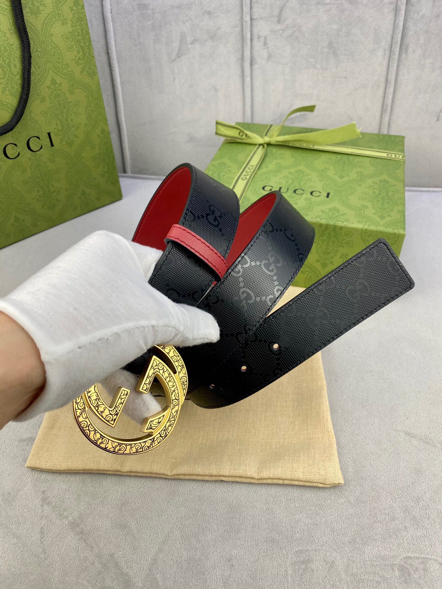 Gucci belt with dark logo strap, red leather lining, gold-tone buckle