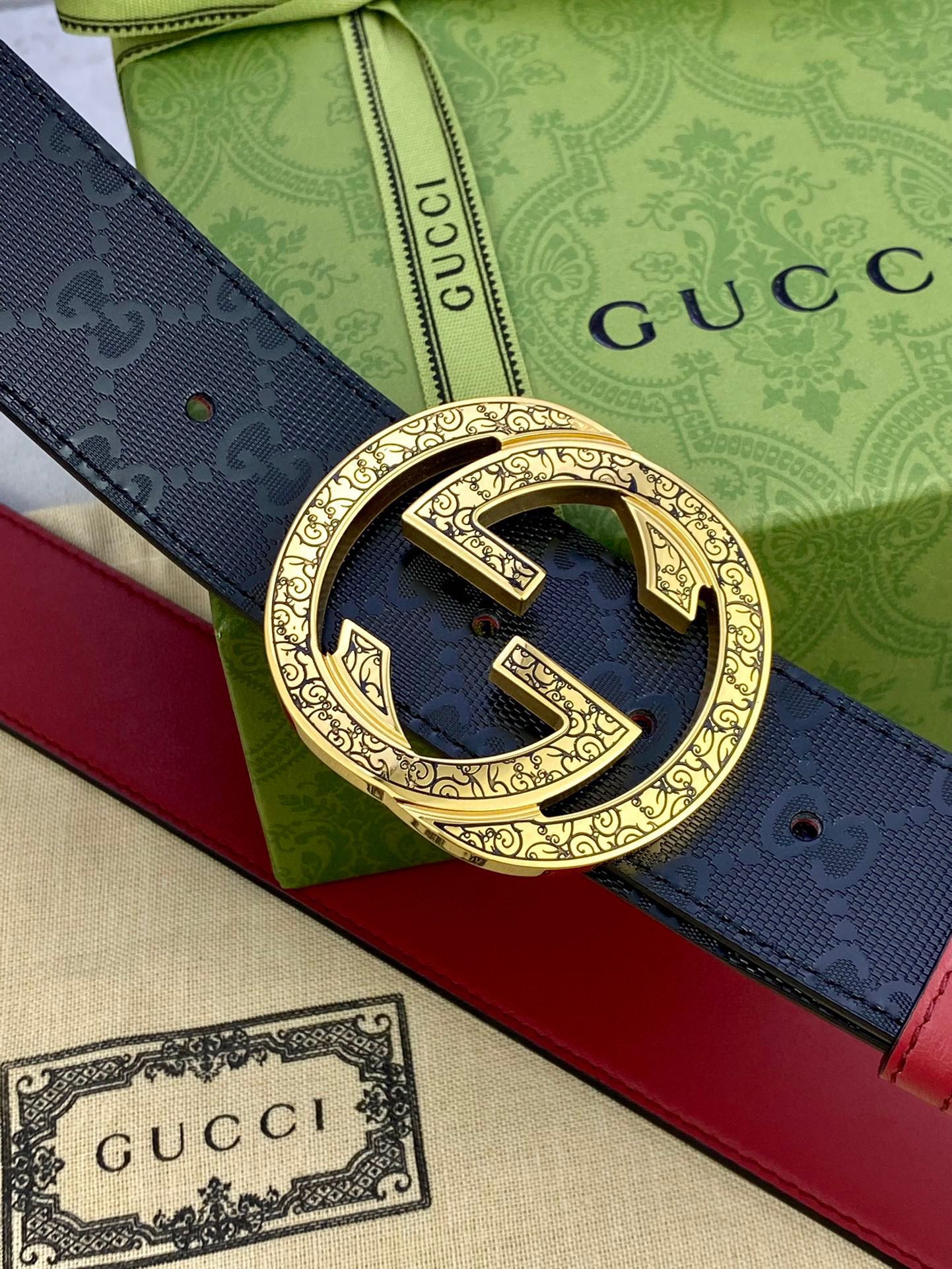 Gucci belt buckle close-up, gold-tone G on dark blue strap with red leather backing