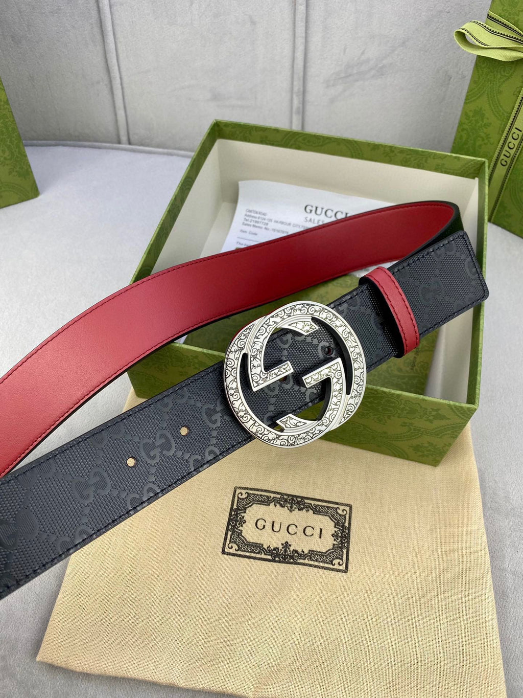 Gucci belt with dark logo strap, red underside, ornate gold-tone G buckle