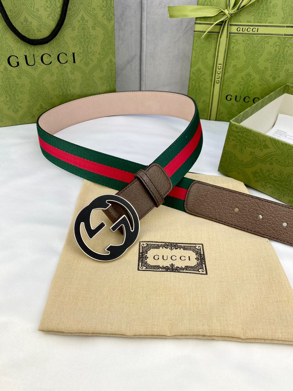 Gucci belt laid flat: beige leather strap, green-and-red web stripe, and gold-tone circular buckle.
