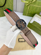 Gucci belt worn on a model’s hand: brown leather, green-and-red web stripe, gold-tone buckle.