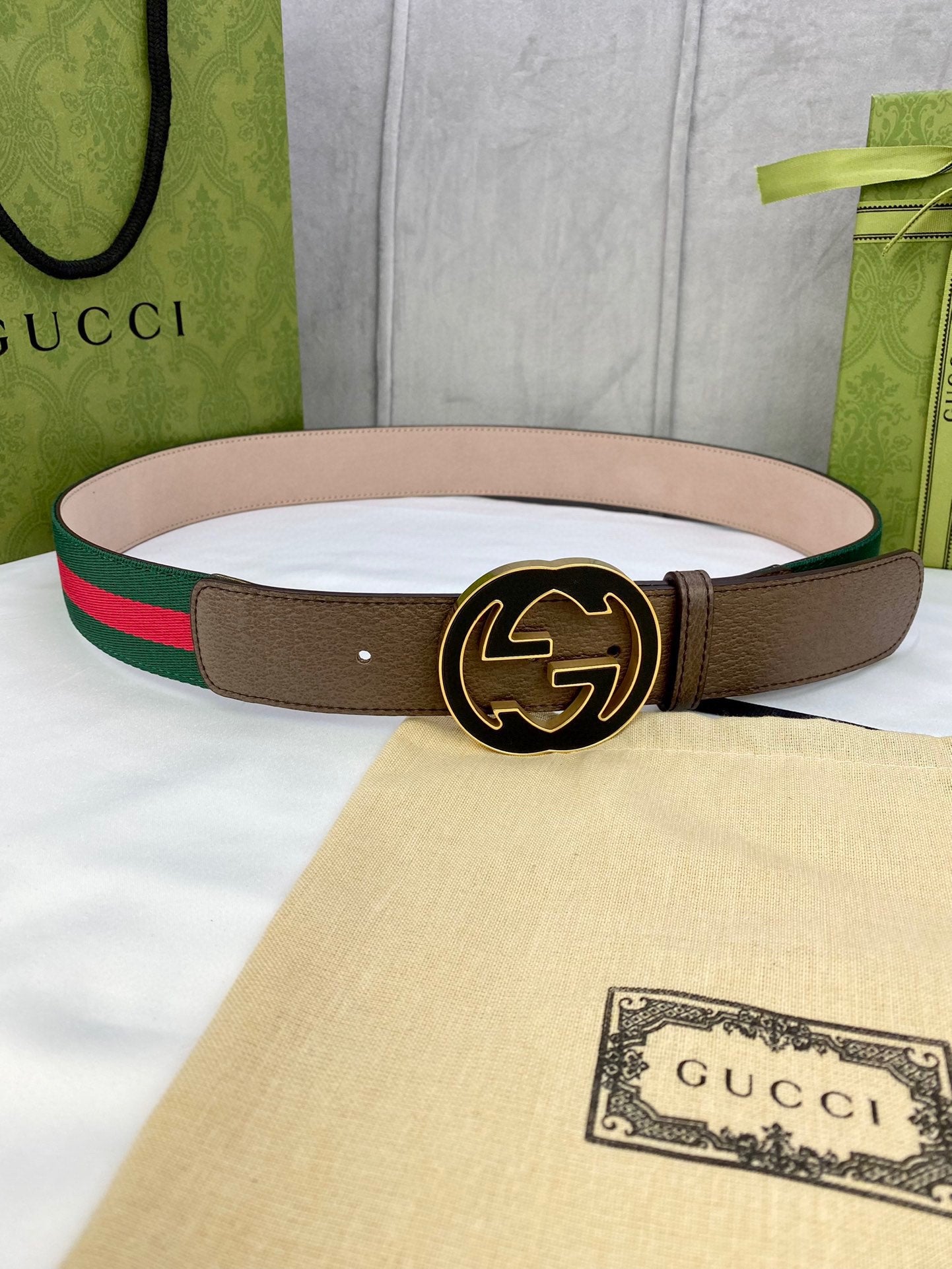 Gucci belt with brown leather strap, green-and-red web stripe, and round gold-tone buckle.