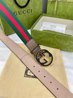 Gucci belt with beige leather, green-and-red web stripe, and round gold-tone GG buckle.