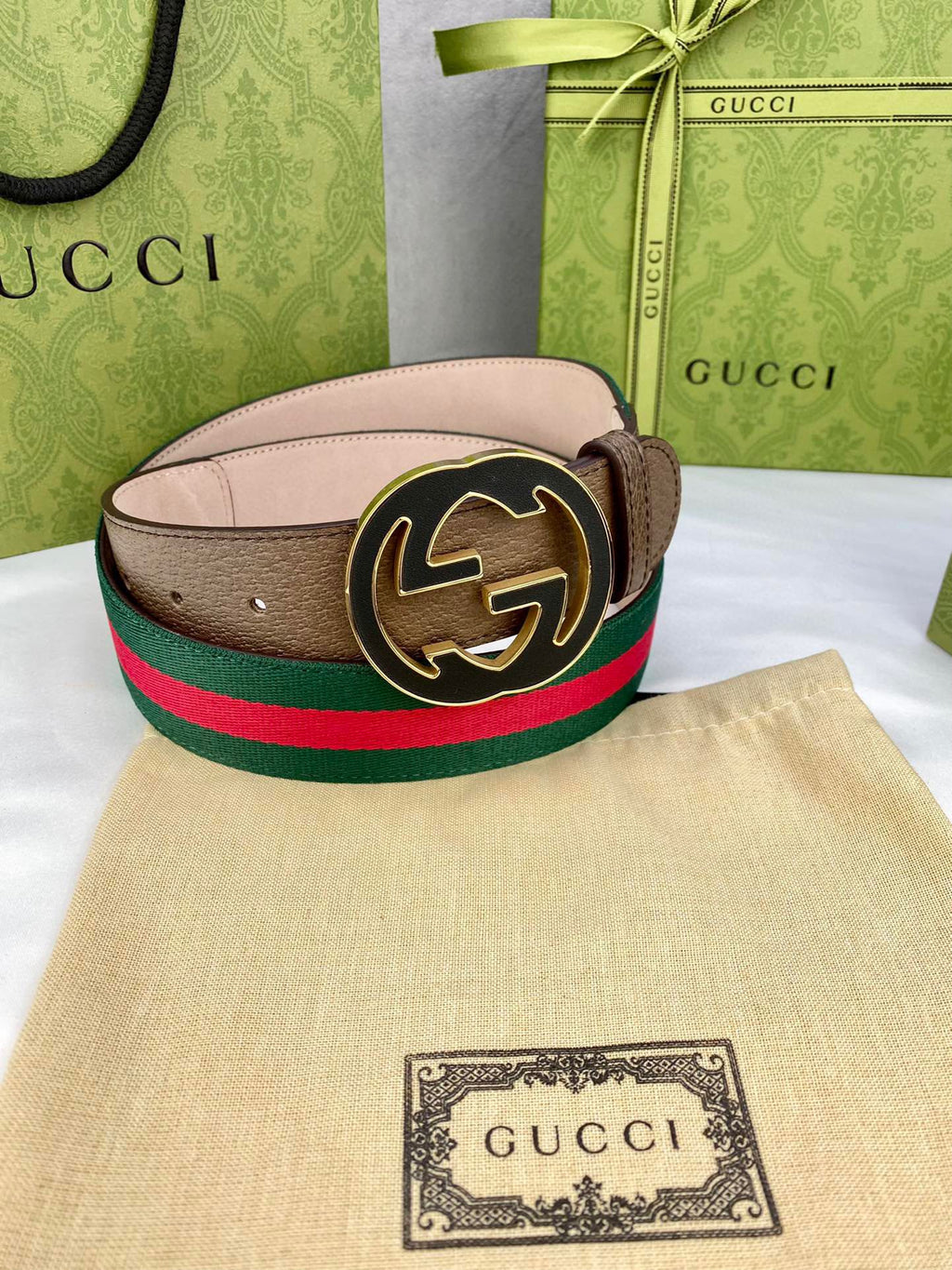 Gucci belt featuring brown leather strap, green and red web stripe, and round gold-tone buckle.