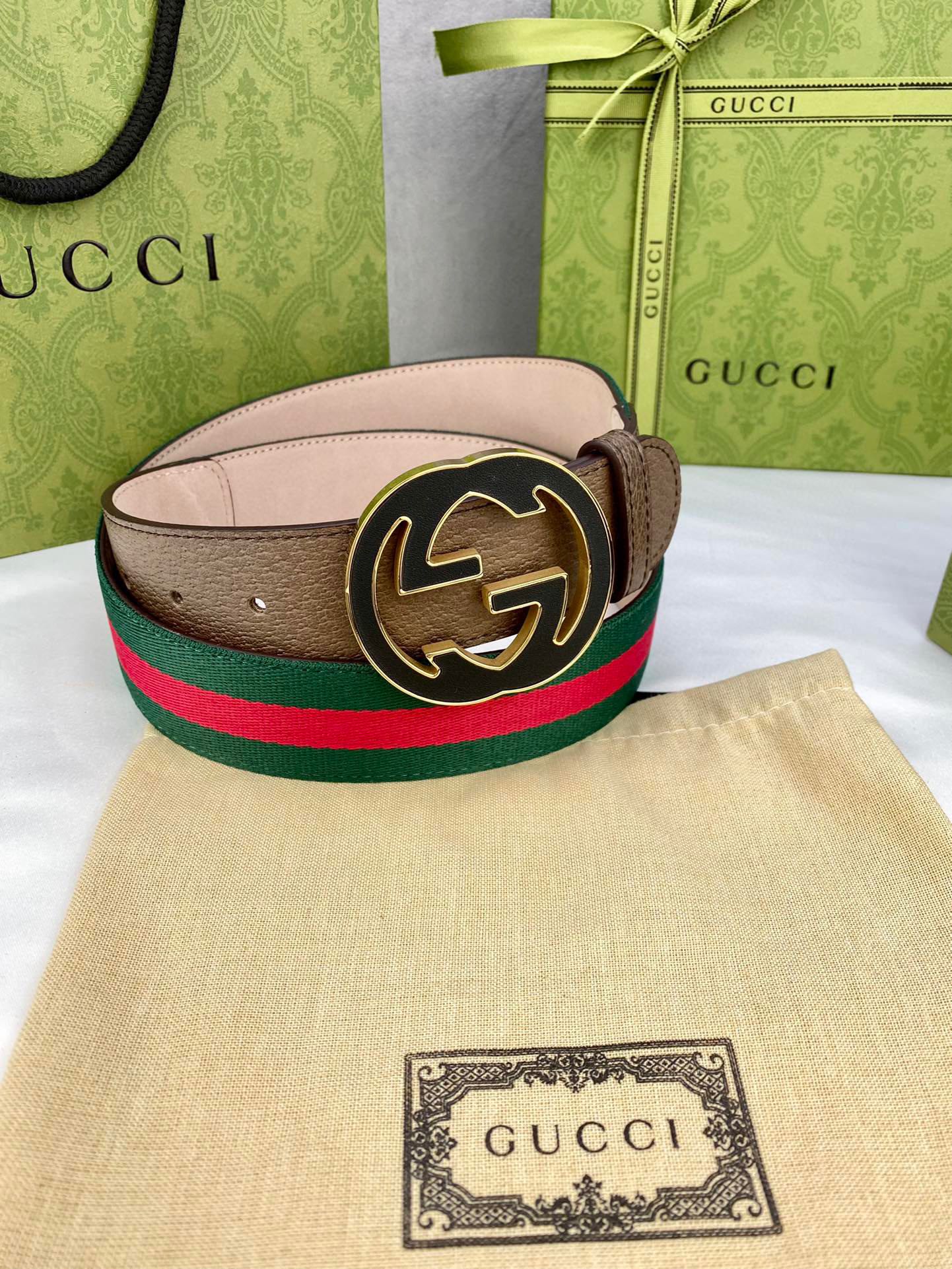 Gucci belt featuring brown leather strap, green and red web stripe, and round gold-tone buckle.