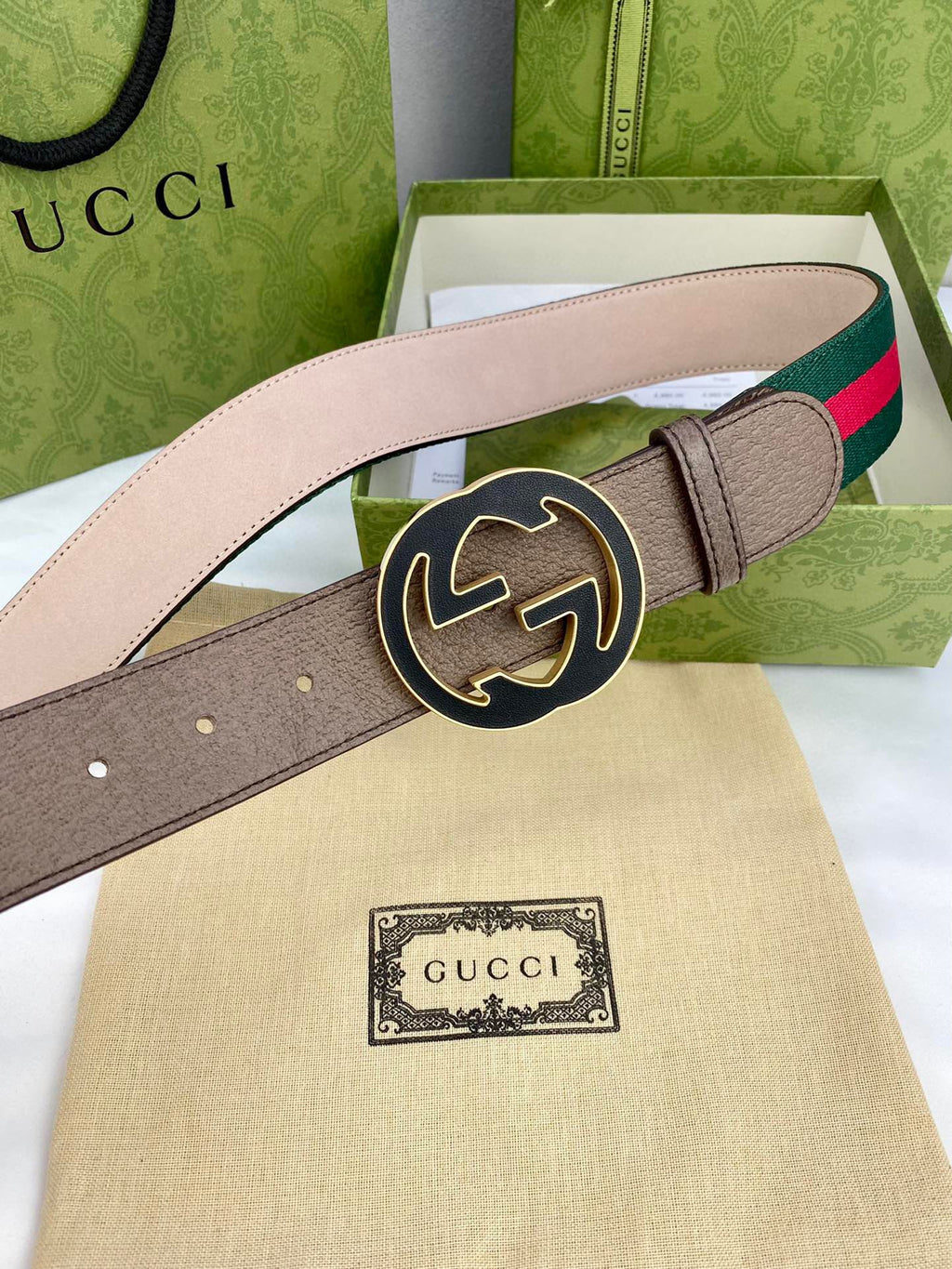 Gucci belt with tan leather, green-and-red web stripe, and large gold-tone circular buckle.