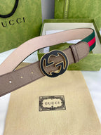 Gucci belt with tan leather, green-and-red web stripe, and large gold-tone circular buckle.