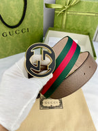 Gucci belt detail with dark brown leather and multicolor web stripe, featuring a gold-tone buckle.
