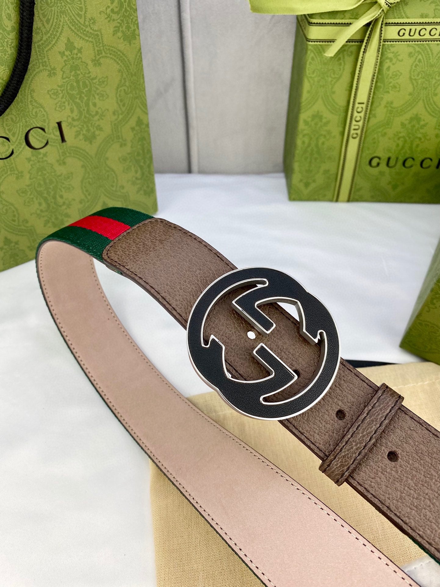 Gucci belt angle view with brown leather, green-and-red web stripe, and large circular GG buckle.