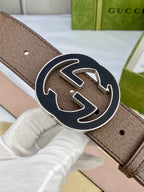Gucci belt close-up of brown leather and large gold-tone circular GG buckle with dark outline.
