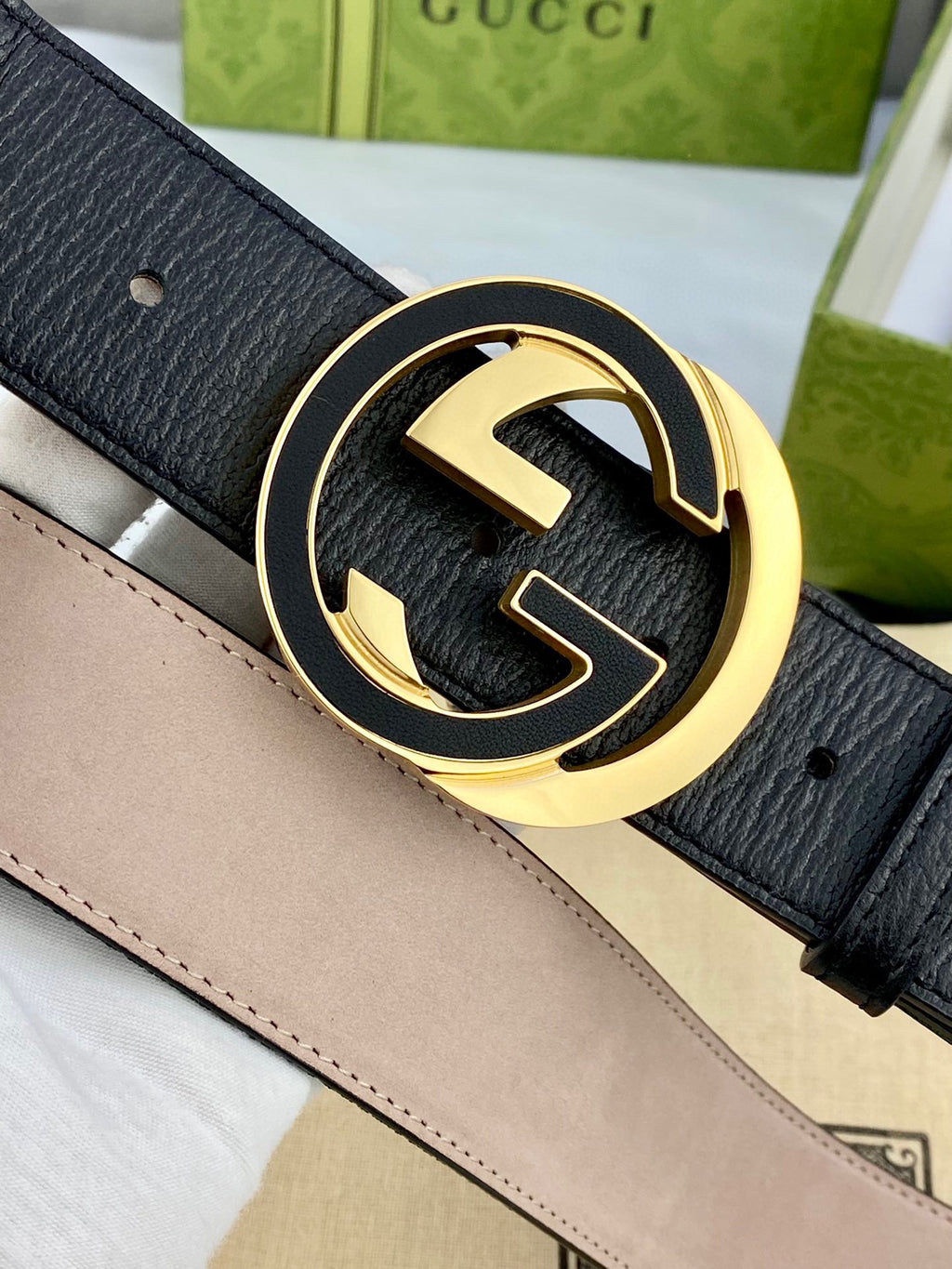 Black leather belt close-up with gold-tone GG buckle and stitched edge trim