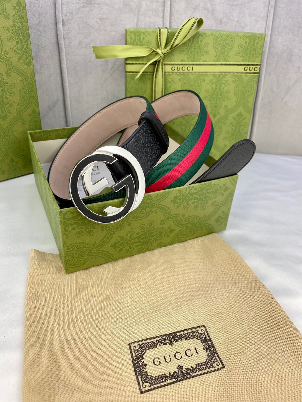 Leather belt with black strap, circular gold-tone buckle, green and red web stripe