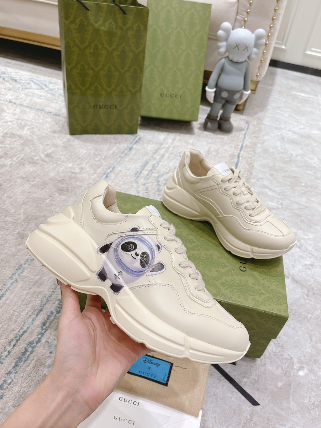 Gucci unisex white sneakers with panda face graphic, held in hand