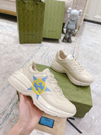 White Gucci unisex sneakers with blue star GG logo, held in hand beside box