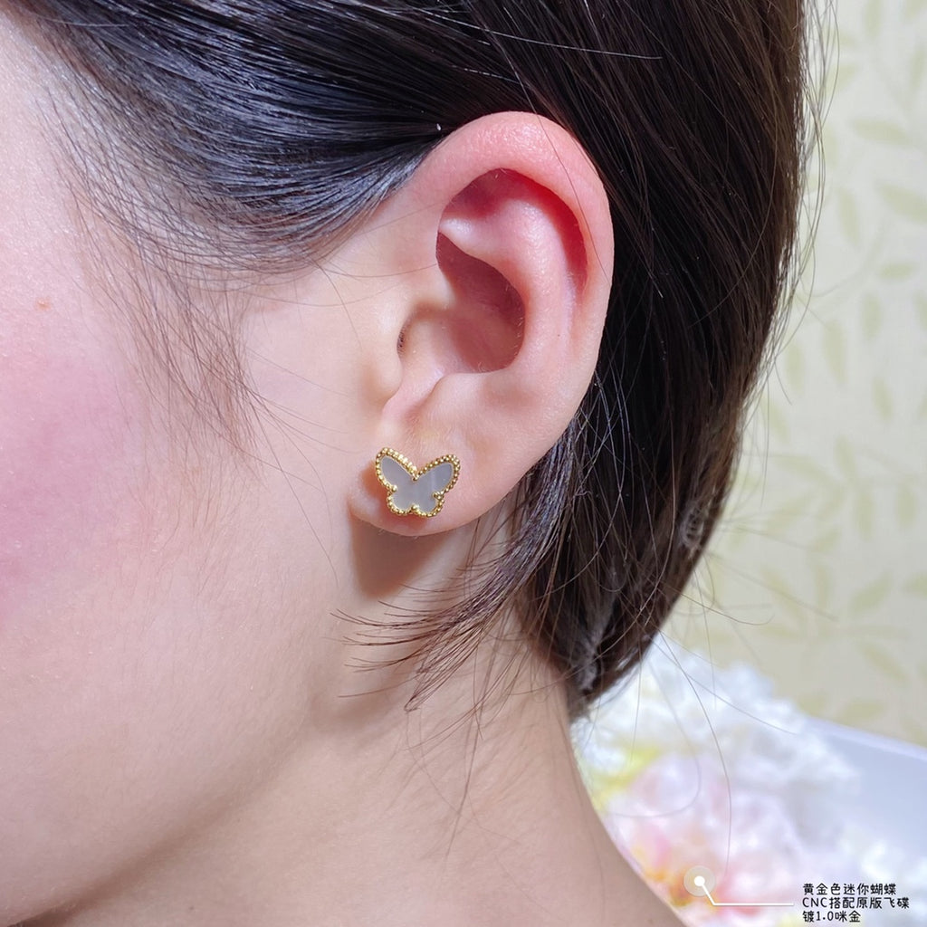 Gold butterfly stud earring with a beaded border on the ear