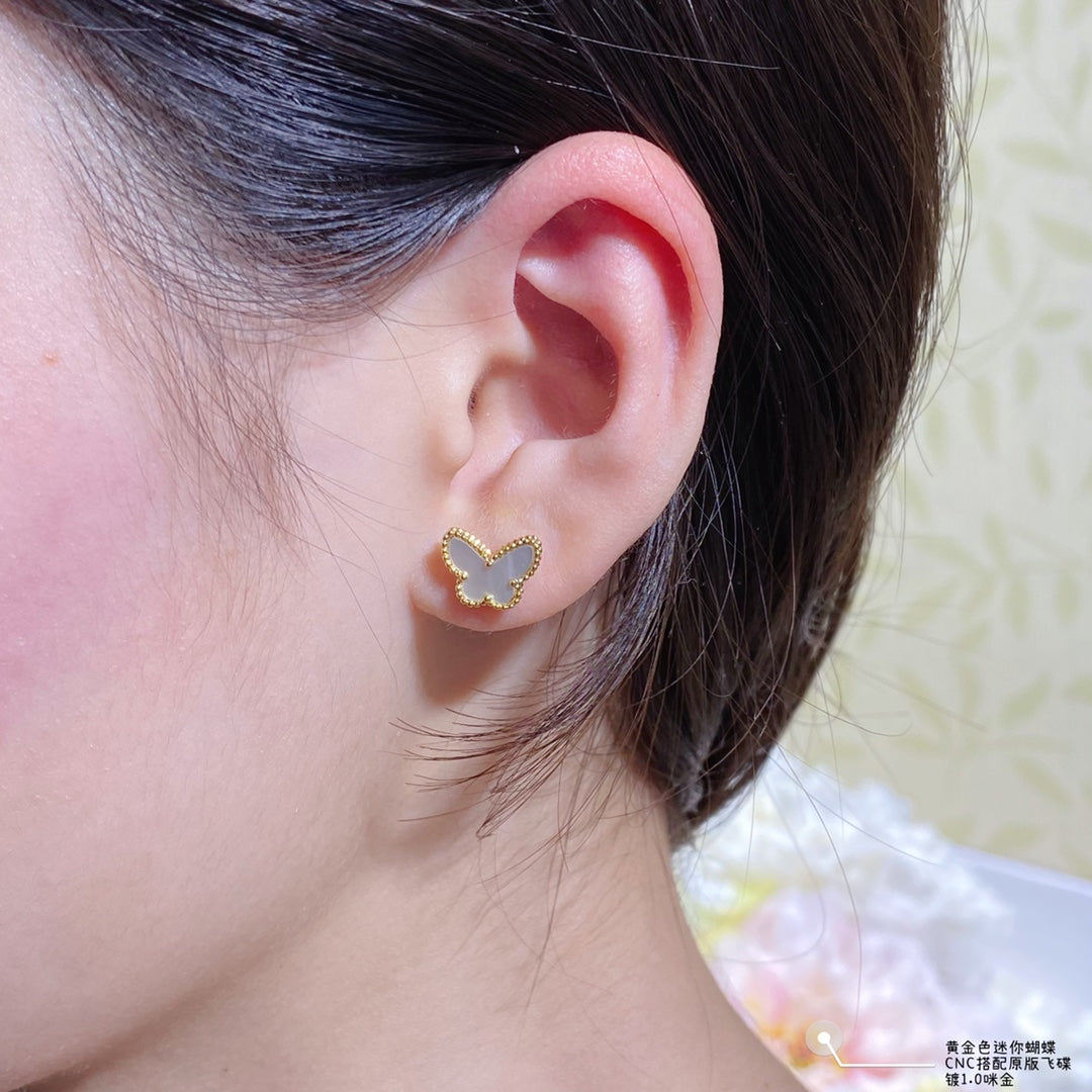 Gold butterfly stud earring with a beaded border on the ear
