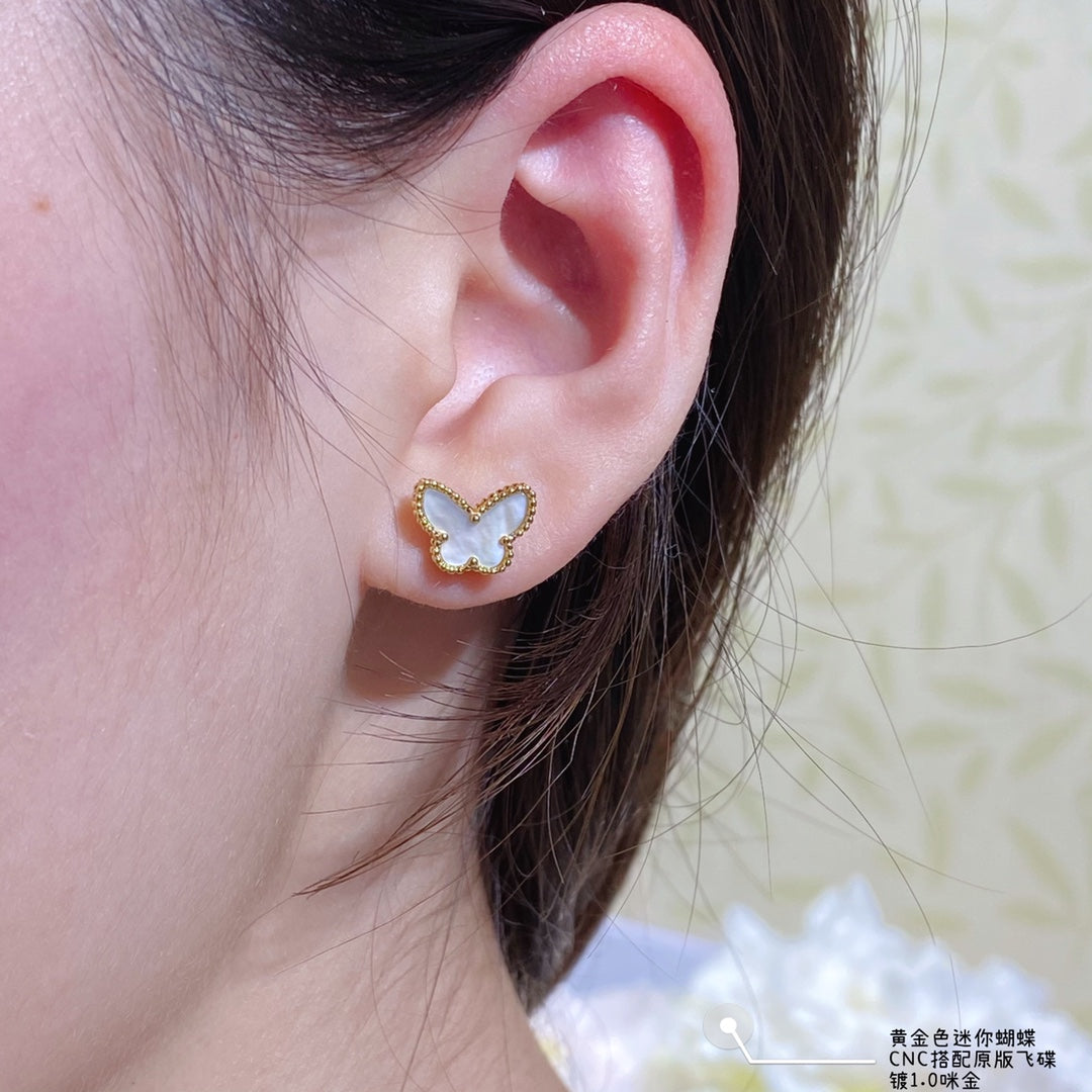 Gold butterfly stud earrings on a visible ear
