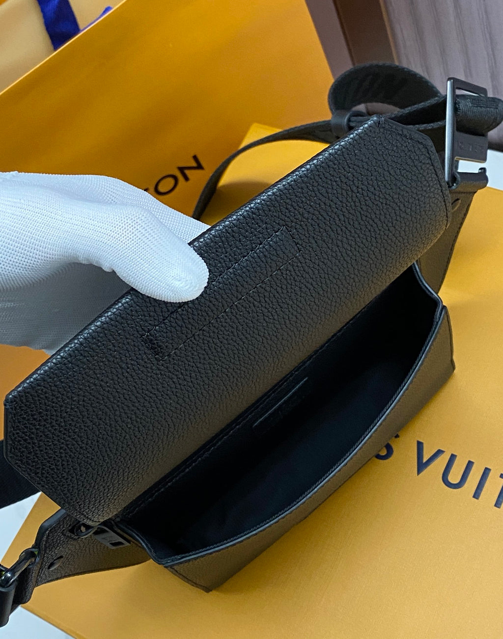 Louis Vuitton crossbody bag close-up with dark leather strap and front flap edge