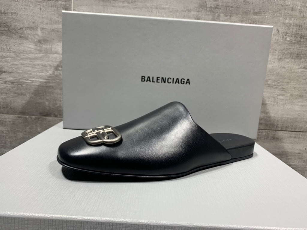 Black leather slide sandal with silver buckle detail on a white box