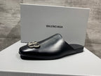 Black leather slide sandal with silver buckle detail on a white box
