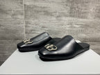 Two black leather slide sandals with silver buckle hardware detail